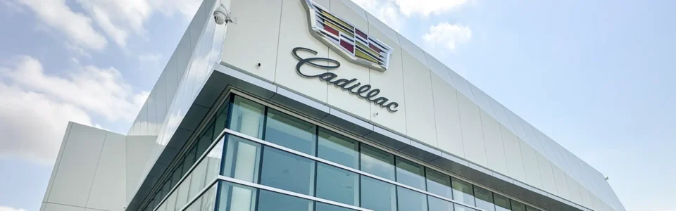 A Cadillac dealership building in Winnipeg, Manitoba, photographed from a low angle. The exterior features aluminum composite siding panels and large glass windows.